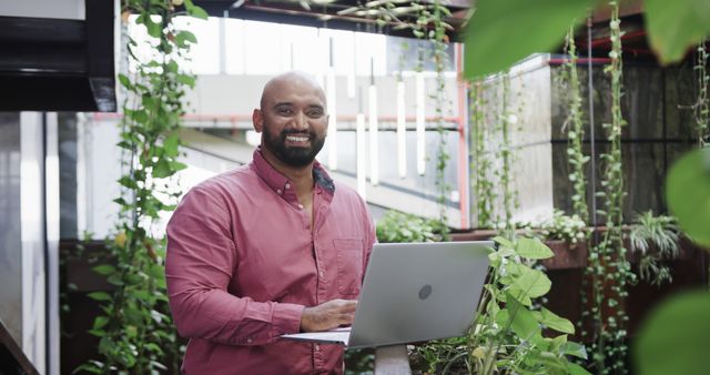 Smiling Man Using Laptop in Modern Indoor Garden Workspace - Download Free Stock Images Pikwizard.com