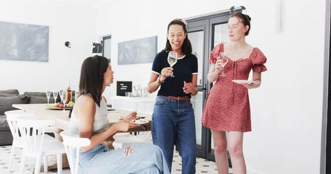Diverse Female Graduates Celebrating with Wine in Bright Dining Room