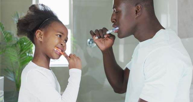 Image of african american father and daughter brushing teeth. Enjoying quality family time together at home.