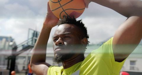 Basketball Athlete Holding Ball Overhead on Outdoor Court