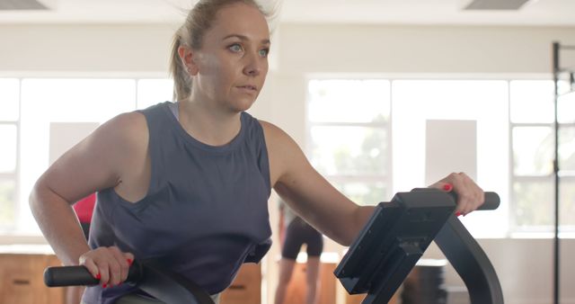 Focused Woman Exercising on Stationary Bicycle at Gym - Download Free Stock Images Pikwizard.com