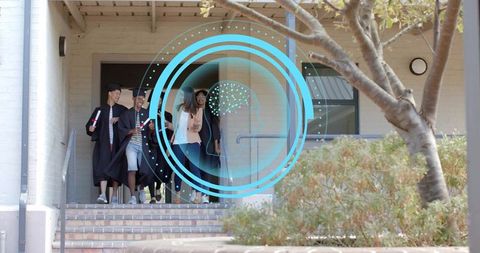 Graduates descending campus steps celebrating commencement with mortarboards and diplomas