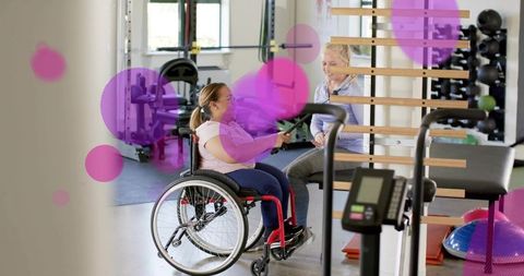 Adaptive resistance band workout with wheelchair client and trainer in rehabilitation gym