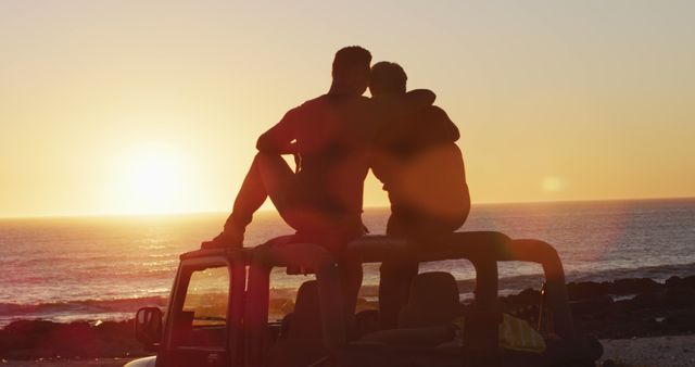 Happy caucasian gay male couple sitting on car roof embracing at sunset on the beach. summer road trip and holiday in nature.
