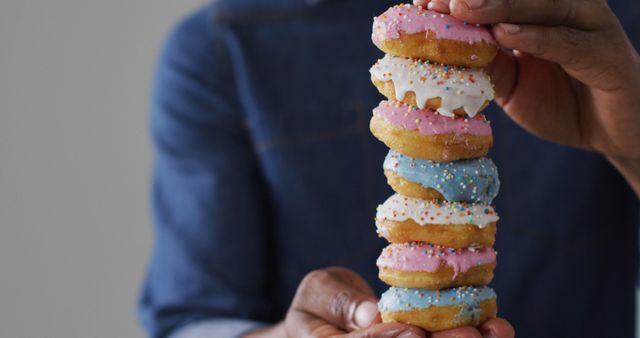 Close-up of Hands Stacking Colorful Frosted Donuts - Download Free Stock Images Pikwizard.com