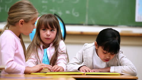 Young Students Collaborating in Classroom Reading Activity