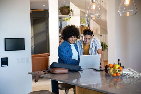 Male Friends Enjoying Technology Interaction at Stylish Kitchen Island