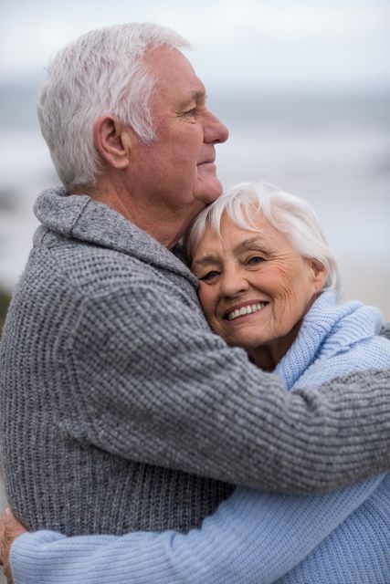 Senior couple embracing on a beach, showing love and happiness. Ideal for use in advertisements, articles, or websites focused on senior living, retirement, relationships, and outdoor activities.