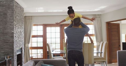Father Lifting Daughter in Living Room During Family Time