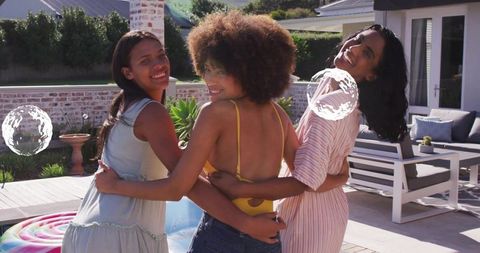 Smiling friends linking arms at backyard pool party on sunny summer afternoon