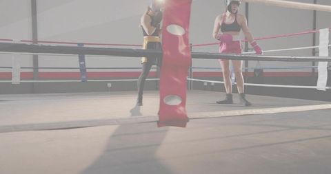 Female boxers sparring in gym ring with red corner post and contrasting gloves