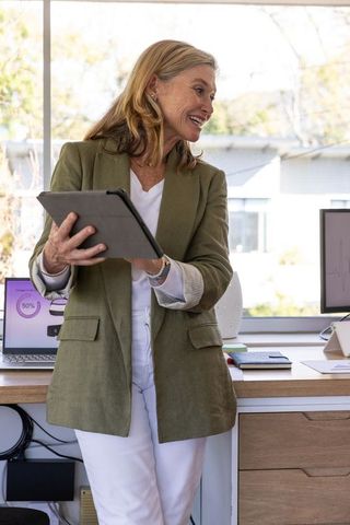 Senior professional presenting with tablet in office setting