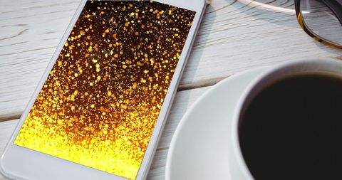 smartphone displaying golden light trails with coffee cup - Download Free Stock Images Pikwizard.com