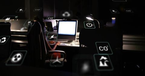 Tech Engineer at Night With Floating Eco Icons in Dark Office