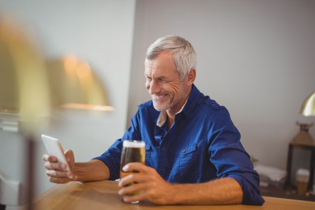 Mature man using mobile phone while having beer - Download Free Stock Photos Pikwizard.com
