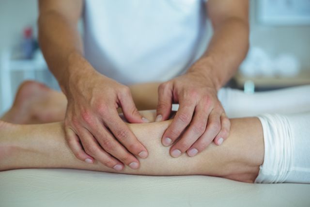 Physiotherapist massaging woman's leg in a clinical setting. Useful for illustrating healthcare, physical therapy, rehabilitation, and wellness topics. Ideal for medical websites, brochures, and articles about physiotherapy and recovery.
