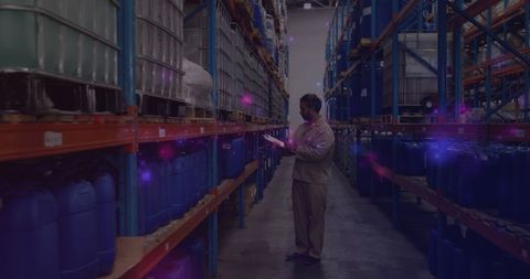 Worker Checking Inventory by Pallets in Warehouse with Glowing Lights
