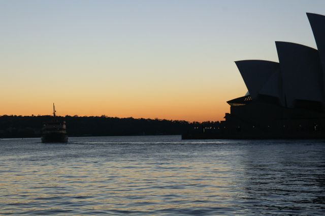 Sydney Harbour ferry sailing at dusk with Opera House in silhouette. Perfect for travel guides, Australian tourism, cityscape art.