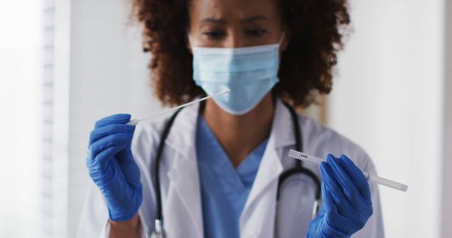 Medical professional is preparing a COVID-19 test sample while wearing protective gear, including gloves and a mask. Can be used in healthcare-related articles, COVID-19 awareness campaigns, or medical facility brochures.