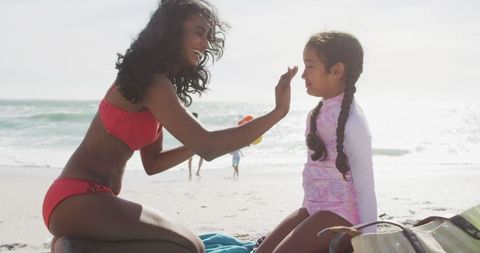 Mother Applying Sunscreen to Daughter at Beach for Safe Sunbathing