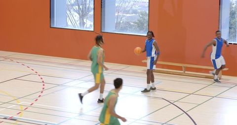 Diverse Players Engaged in Intense Indoor Basketball Game
