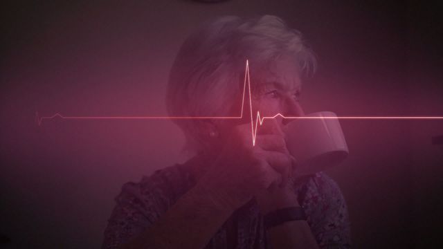 This video shows a caucasian senior woman drinking coffee at home with a digital heartbeat line overlay. Ideal for use in healthcare materials, retirement lifestyle projects, medical articles, or wellness advertisements. This visually striking combination symbolizes health monitoring, careful healthcare management, and the importance of a balanced lifestyle for elderly individuals.