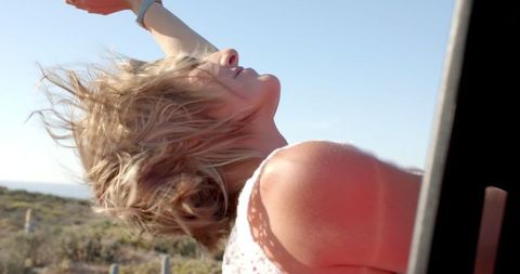 Young Woman Enjoying Windblown Freedom in Sunny Day Road Trip