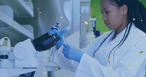 Laboratory scientist pipetting liquid, focusing at bench with microscope wearing blue gloves