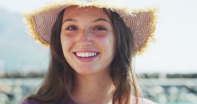 Portrait of happy caucasian teenage girl in sunhat smiling to camera on sunny day. Leisure, free time, travel and vacations.
