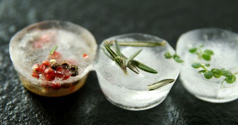 Artistic herb and berry infused ice on dark surface