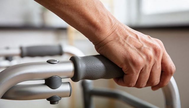 Senior hand gripping padded walker handle demonstrating mobility support and independence