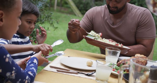 Family Enjoying Outdoor Meal in Garden on a Sunny Day - Download Free Stock Images Pikwizard.com