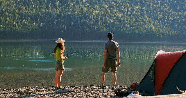 Man and woman standing at lakeside campsite enjoying nature - Download Free Stock Images Pikwizard.com
