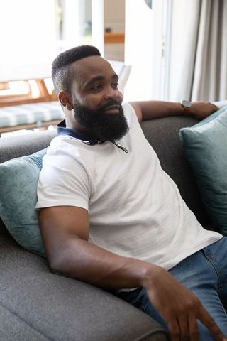 Relaxed African American Man Sitting Comfortably on Sofa at Home