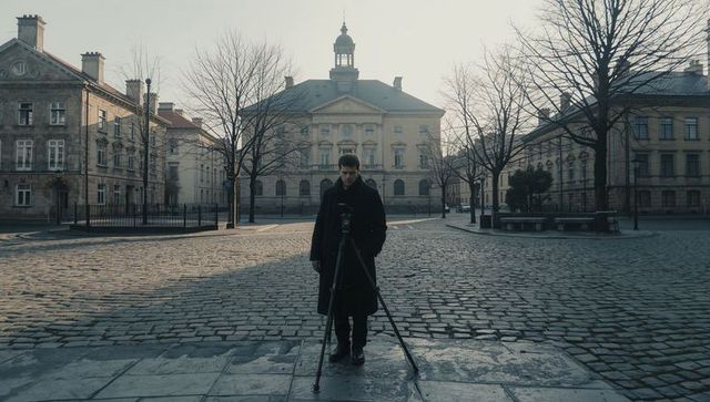 Photographing man operating tripod in neoclassical cobblestone square with cupola