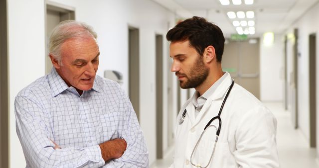 Doctor Discussing Report with Elderly Patient in Hospital Corridor - Download Free Stock Images Pikwizard.com