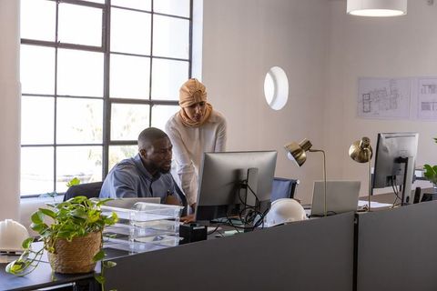 Diverse Teams Collaborating on Architectural Plans in Office