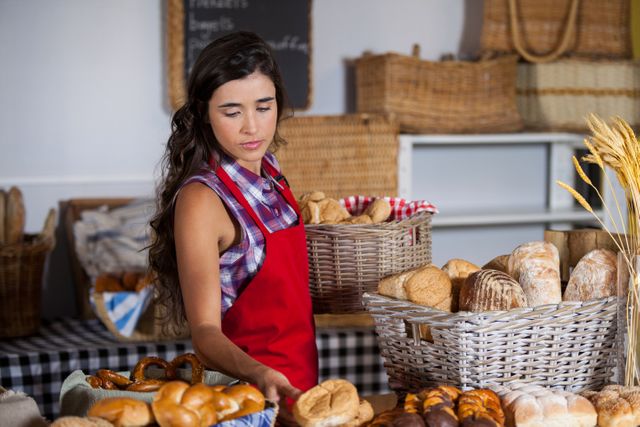 Female staff holding basket of sweet foods in bakery section of supermarket