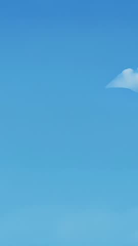 Vertical video capturing cumulus cloud drifting across clear blue sky with calm copy space