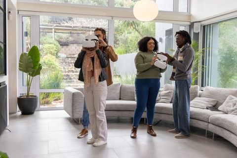 Friends trying vr headsets testing virtual reality in bright modern living room with curved sofa
