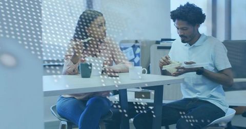 Colleagues sharing lunch in modern office breakroom with takeout and dotted glass divider