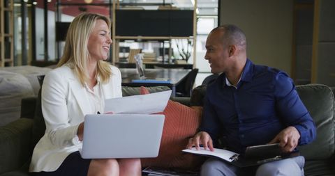 Colleagues Discussing Work with Laptop and Papers in Modern Office Setting