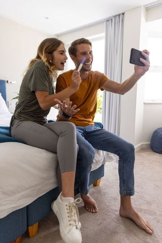Joyful couple sharing pregnancy news with selfie