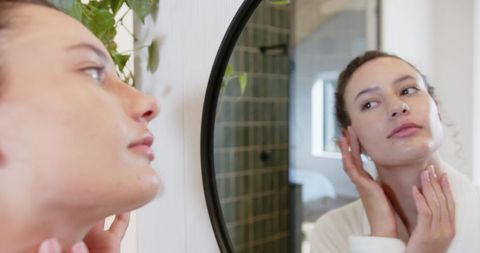 Woman Practicing Skincare in Bright Modern Bathroom