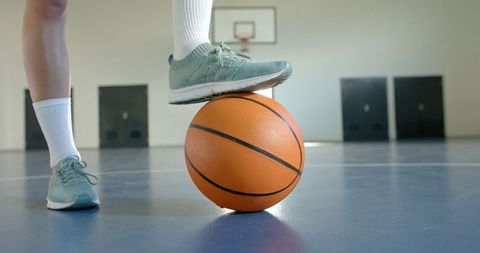 Female Athlete Balancing on Basketball in Indoor Court