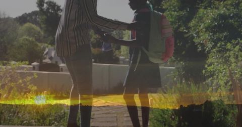 Mother Adjusting Daughter’s Backpack in Sunny Front Yard
