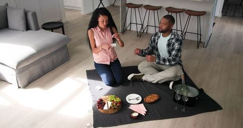 Couple Enjoying Indoor Picnic with Gift Exchange and Celebration
