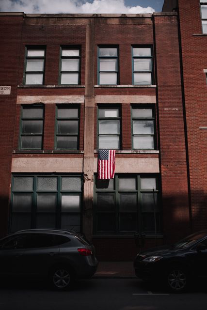 United States flag hanging on old brick building in urban neighborhood - Download Free Stock Photos Pikwizard.com