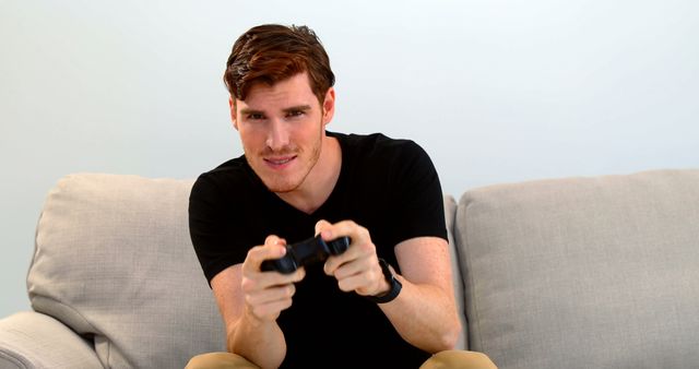 Young man playing video games intensely on couch - Download Free Stock Images Pikwizard.com