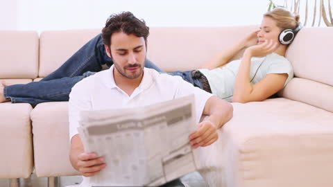 Couple Enjoys Relaxing Moment at Home with Newspaper and Music